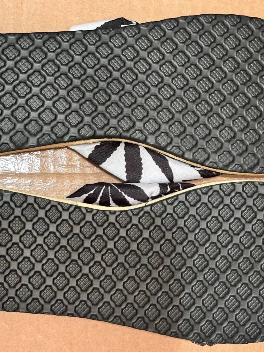 Fashion brand flip-flops feature a white fabric strap decorated with a black lea